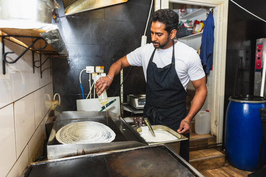 Chef spreading oil on grill for dosa cooking