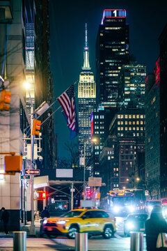 Vibrant NYC nightscape with taxi, flags and empire state