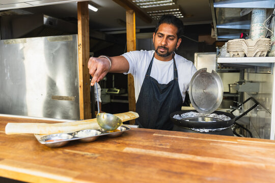 Chef plating large dosa at restaurant counter