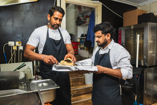 Indian restaurant staff wrapping takeaway food