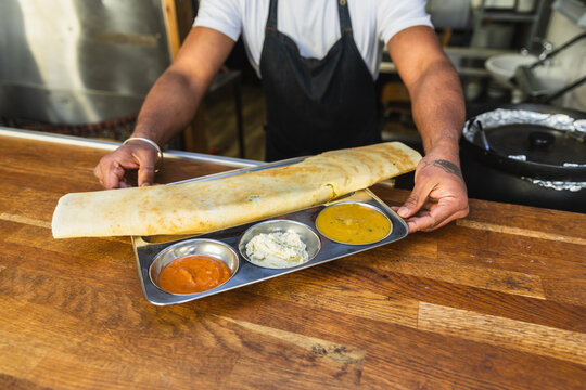 Hands holding traditional Indian dosa thali tray