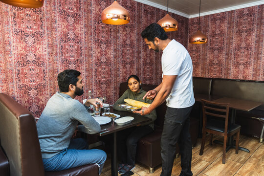 Indian waiter serving dosa to couple