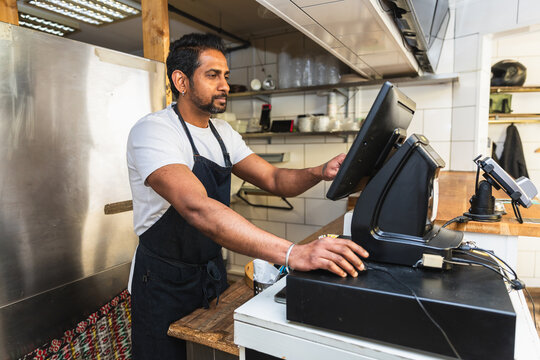 Indian manager working at POS terminal