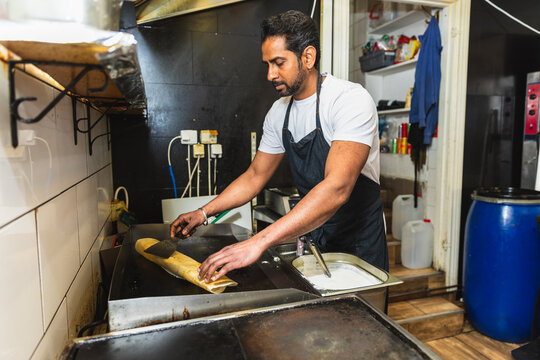 Chef rolling a crispy dosa on the grill