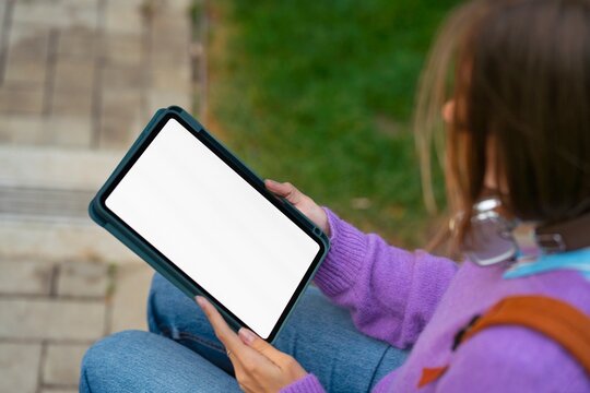 Person holds tablet while sitting on outdoor steps