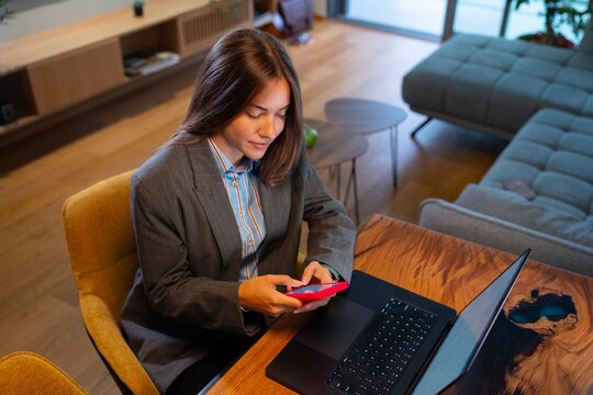 Woman working with laptop and phone at home office