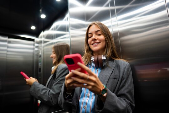Woman using smartphone in elevator during day