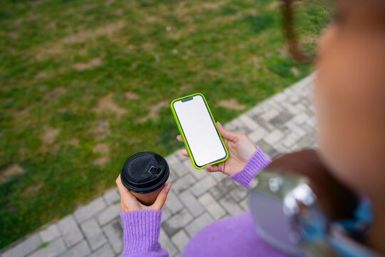 Holding phone and coffee in park setting