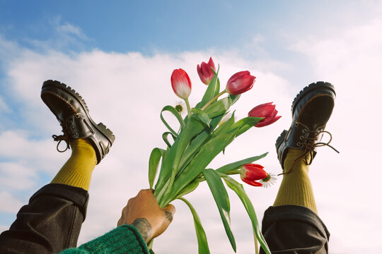 Holding flowers while lying on the ground with feet in the air