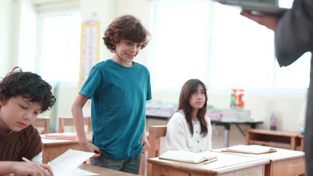 Confident boy standing and speaking in diverse classroom. Elementary school student giving a presentation or self introduction to teacher and classmates.