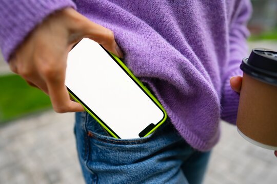 Person holds coffee and checks phone outside
