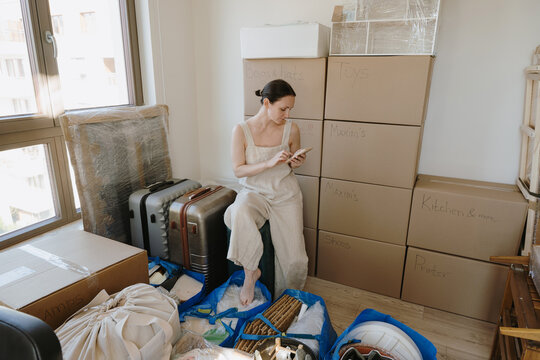 Woman scrolling phone and preparing for a house move