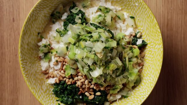 Adding Cooked Vegetables To Spinach Feta Bowl Top View