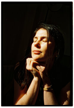 Woman with closed eyes illuminated by sunlight
