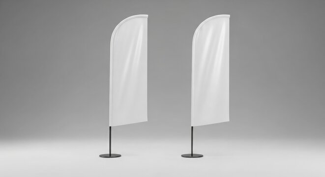 Pair of blank white feather flags standing isolated on simple neutral gray studio.