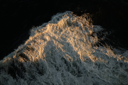 Ocean waves reflect sunlight during early evening hours