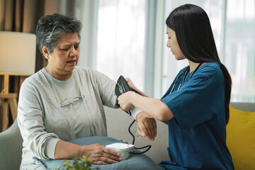 Fototapeta premium Healthcare Professional Measuring Blood Pressure of Senior Woman at Home. Home healthcare, blood pressure monitoring, senior wellness