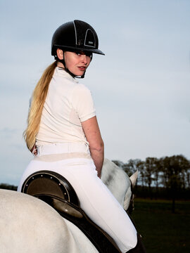 Rider in White Outfit Turning Back on Horse During Sunset