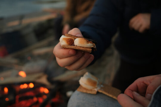 Making s'mores by the campfire at sunset with family and friends