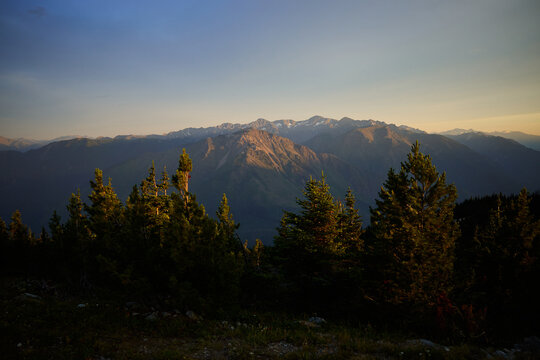 Mountains rise above trees at sunset in a quiet setting