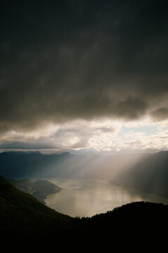 Sunlight breaks through clouds over mountain lake at dusk