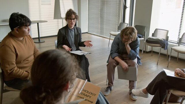 Caucasian female psychotherapist conducting group therapy session for diverse young adults. Video for mental health campaigns and counseling service promotions