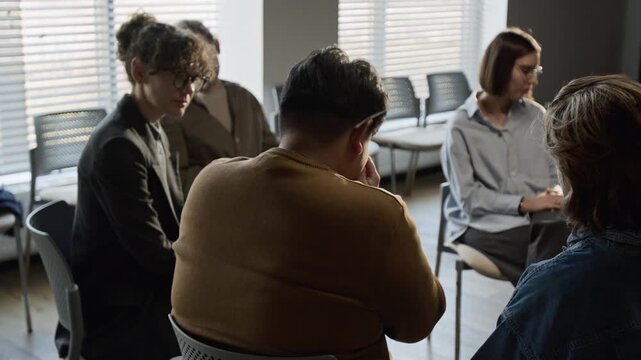 Caucasian man comforting crying Asian guy during diverse support group therapy session. Footage for mental health awareness and psychological counseling commercials