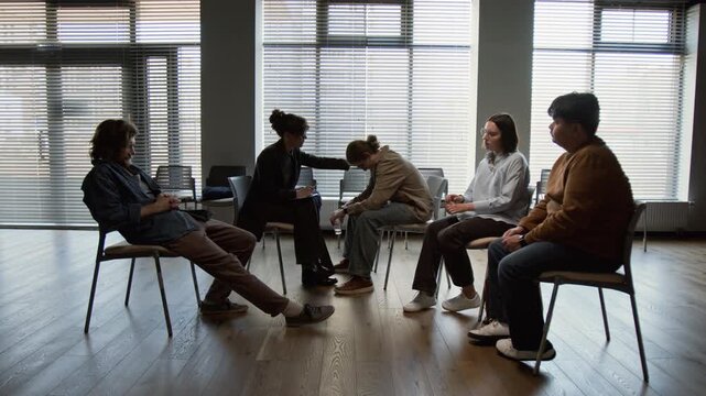 Caucasian female psychotherapist comforting crying Caucasian teenager with glasses during diverse group therapy session. Video for promoting mental health awareness