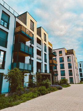 Modern residential apartment building with bicycles at entrance and minimalist contemporary architecture under cloudy blue sky