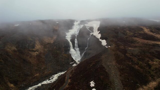 Majestic aerial view of the Rjukandafoss waterfall in the Jokuldalur valley, Iceland. Powerful cascades flow through a misty, snow patched canyon