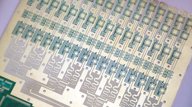 An intricate golden and silver printed circuit board matrix panel showing micro lectronic footprints.