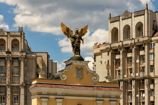 View of the golden statue of Archangel Michael atop the historic Lyadski Gate, surrounded by classic urban architecture under a bright blue sky in Kyiv, Kyiv city, Ukraine.