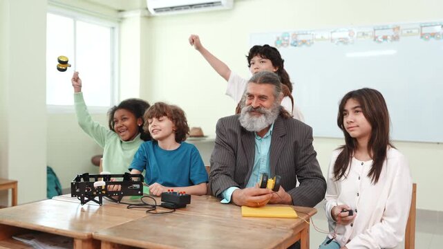 Diverse students and teacher cheering for success in STEM robotics class. Excited children celebrating science and engineering project achievement in elementary school.