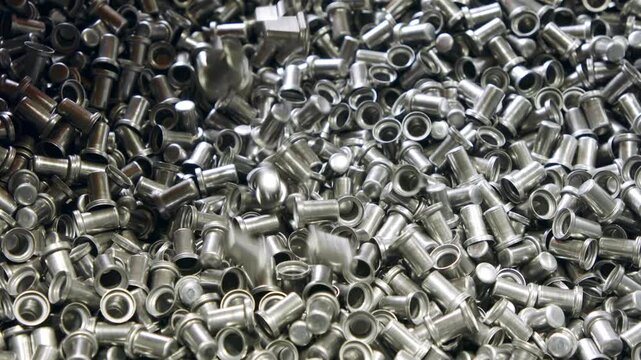 Closeup of a large pile of industrial metal rivets or fasteners in a manufacturing facility