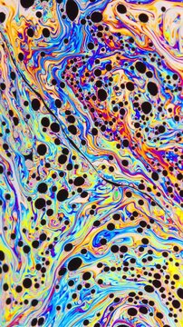 Macro shot of a soap bubble creates a colorful and psychedelic background. Vertical Video.