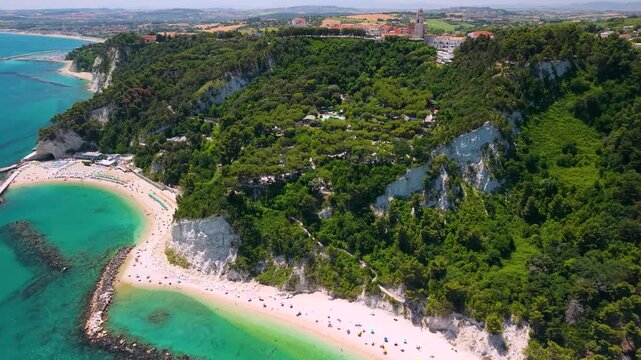 Scenic Sirolo and Numana coastline in Marche Italy aerial drone view featuring crescent cove with vivid turquoise water and hilltop village. Cinematic Riviera del Conero seascape