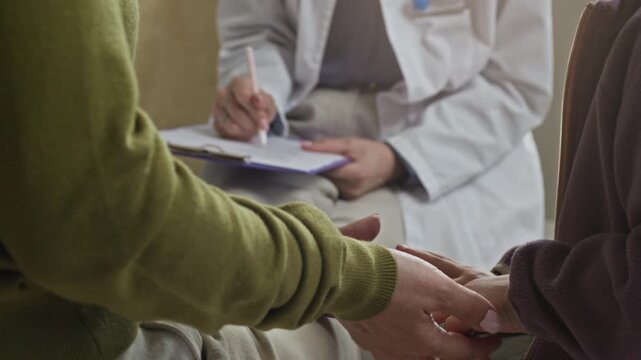 Caucasian mother holding hand of young child while female pediatrician writing notes on clipboard. Perfect for promoting pediatric healthcare services and family medical insurance advertising