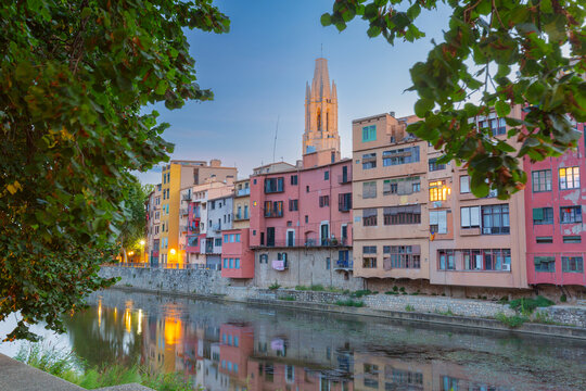 Dawn view of colorful riverside buildings and cathedral bell tower reflected in the Onyar River in the historic center of Girona, Catalonia, Spain.