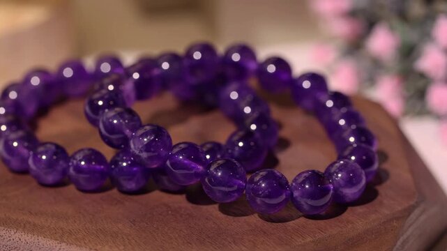 The display shows multiple amethyst stone bracelets arranged on a wooden tray. The focus is on the unique features of each bracelet and the wooden texture.