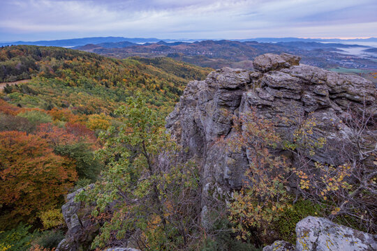 View of rocky formations of Sitno peak overlooking autumn forests and rolling hills under a cloudy sky in the Stiavnicke vrchy mountains Ilija, Banska Bystrica Regio, Slovakia.