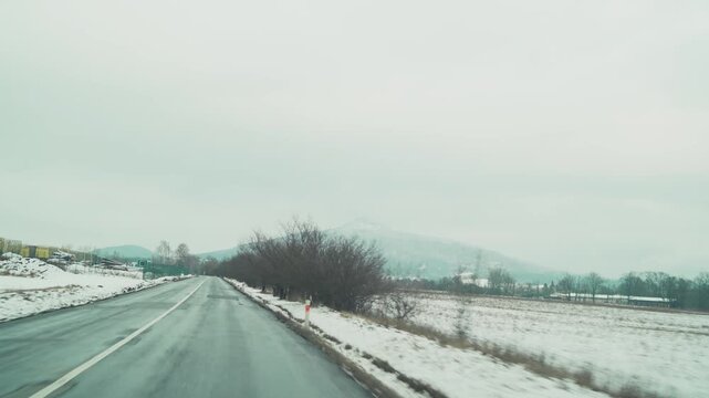 View through windshield while driving from Liberec toward Macha Lake. Road trip in Czech countryside during winter.