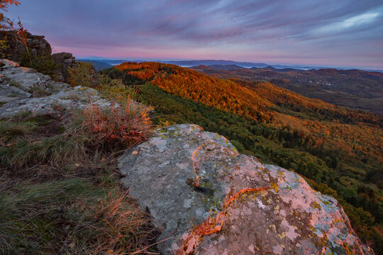 View of rocky cliffs of Sitno peak overlooking autumn forests and hills under a colorful sunset sky in the Stiavnicke vrchy mountains Ilija, Banska Bystrica Region, Slovakia.
