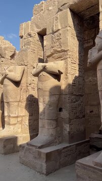 Magnificent row of monumental statues of Ramesses III depicted as Osiris against a clear blue sky at the historic Karnak Temple, an iconic UNESCO World Heritage site in Luxor, Egypt.