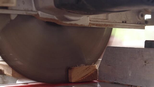 The process of sawing a wooden block with a miter saw. Close-up of the blade in operation. Working with wood, a miter saw cuts a wooden workpiece. The concept of construction and carpentry. Work