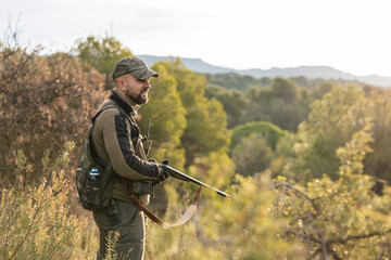 Fototapeta premium Hunter standing with shotgun in nature environment