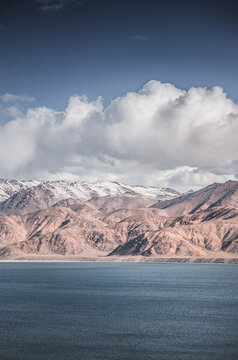 Landscape in the Pamir Mountains with a blue lake Yashilkul in the Tien Shan, a panoramic view of the highlands with snow-capped rocky peaks and the blue waters of the lake