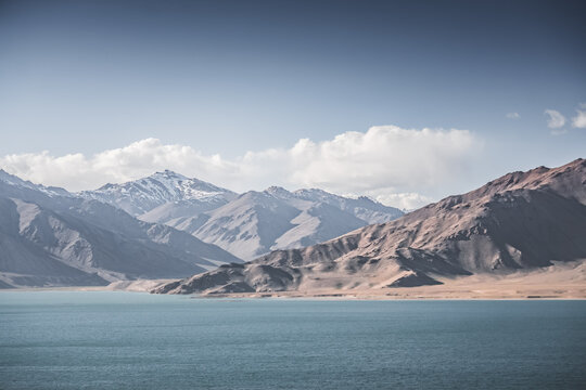 Landscape in the Pamir Mountains with a blue lake Yashilkul in the Tien Shan, a panoramic view of the highlands with snow-capped rocky peaks and the blue waters of the lake
