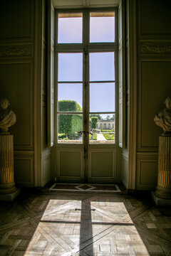 Artistic interior view from within the Petit Trianon, a historic ch&acirc;teau located in the grounds of the Palace of Versailles, France. Strong sunlight creates sharp shadows through the window 