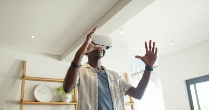 African American man donning white VR headset, manipulating objects while exploring scene at home