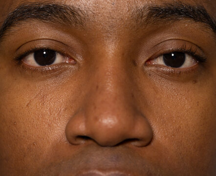 Male staring directly, showing eyes, nose, eyebrows, eyelashes and skin pores in studio